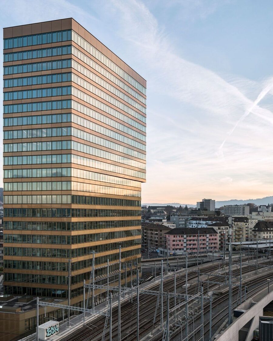 Andreasstrasse 5, a tall dark-grey facade with a regular grid of windows, shot from below against a pale sky.